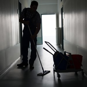 Full length of silhouette man with broom cleaning office corridor